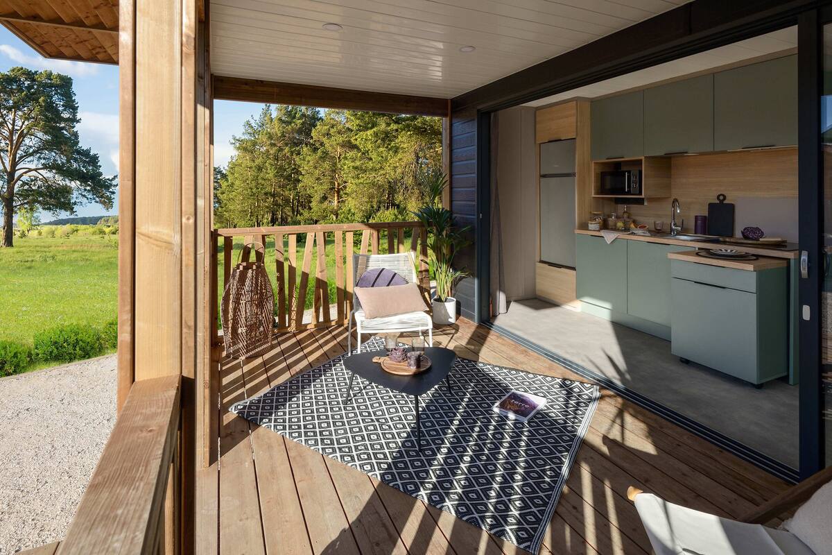 A wooden deck with a dining area, a white chair, and a kitchen with green cabinets.