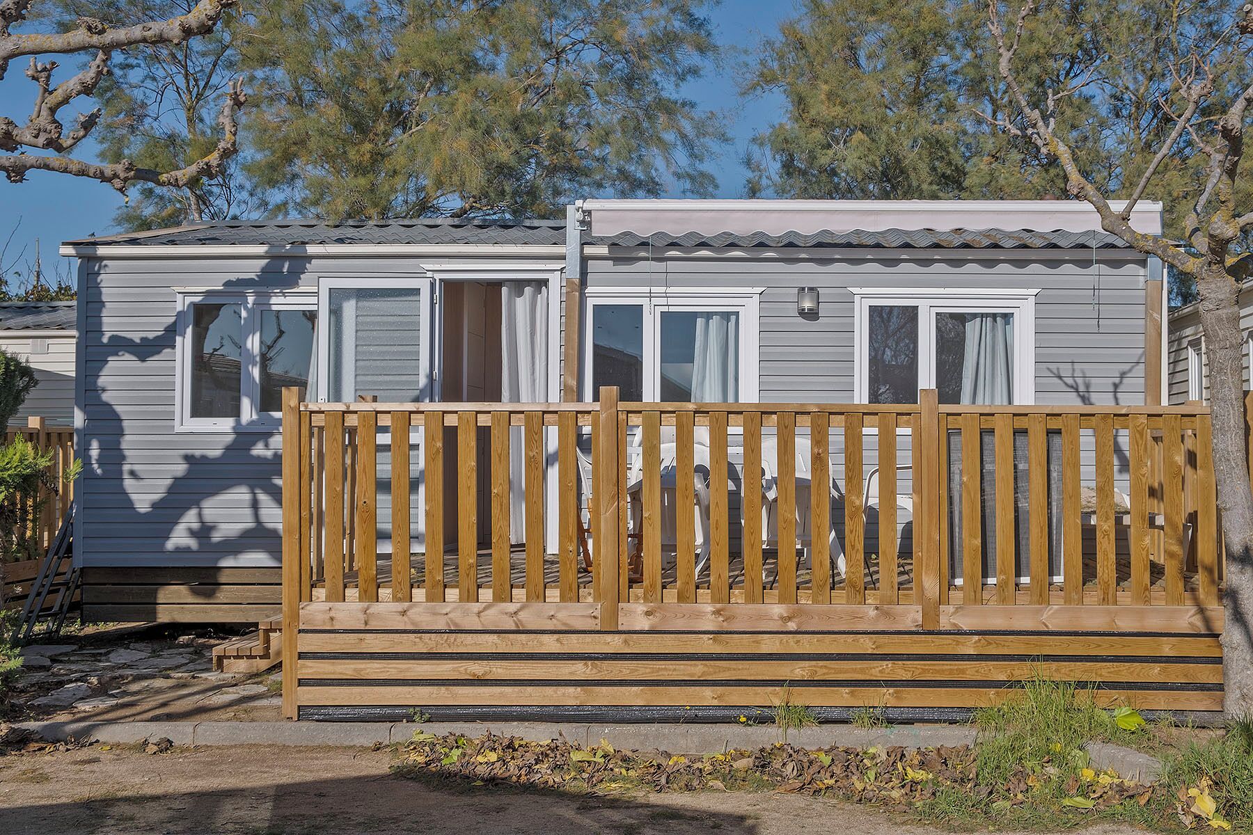 A mobile home with a wooden deck and a fenced area.