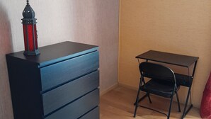 A room with a black dresser, a small black desk, and a red cushion. - Le Menhir  (Avrille)