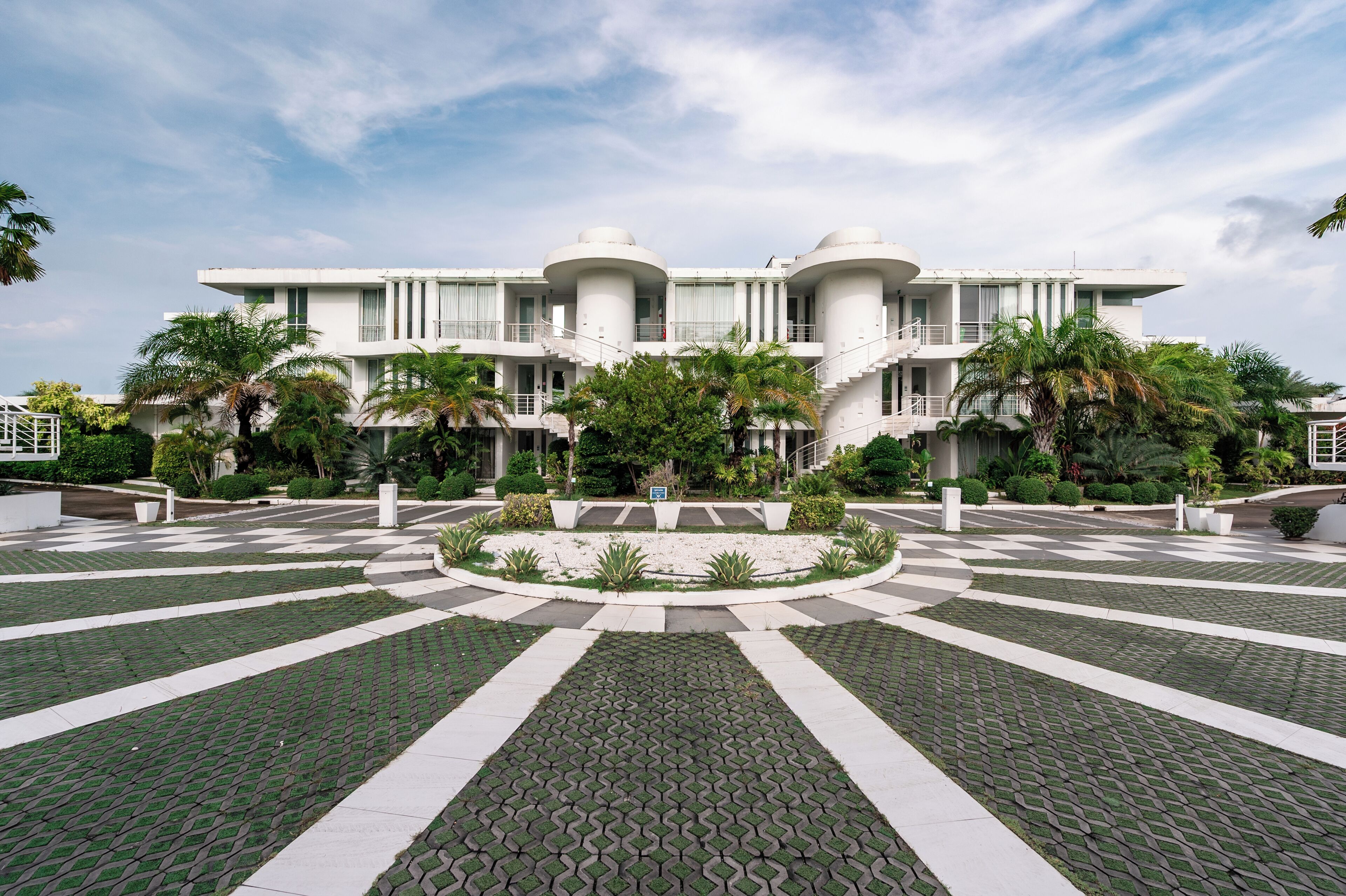 Un edificio moderno con fachada simétrica, varios balcones y un jardín circular central.