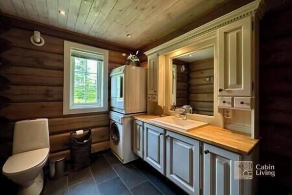A cabin-style kitchen with wooden walls, a built-in sink, and a window.