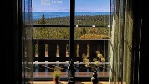 A cabin with a large window offering a view of a forest and mountains.