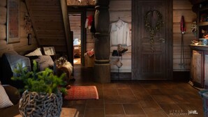 A cozy log cabin interior with a wooden ceiling, a large wooden door with a wreath, a hanging coat rack, and a rustic dining area. - Luxury Cabin at Nesfjellet with sauna, bbq, close to ski & golf (Nesbyen)