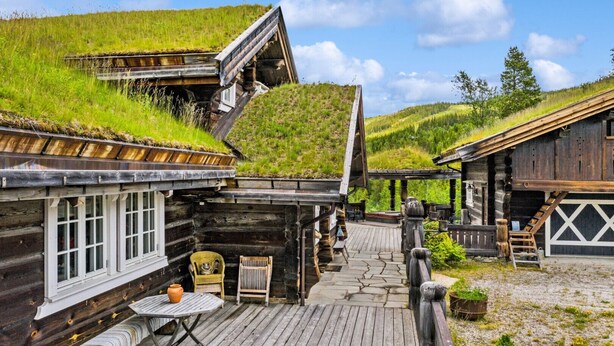 A rustic log cabin with a thatched roof, a wooden deck, and a stone pathway leading to a wooden door. - Luxury Cabin at Nesfjellet with sauna, bbq, close to ski & golf (Nesbyen)