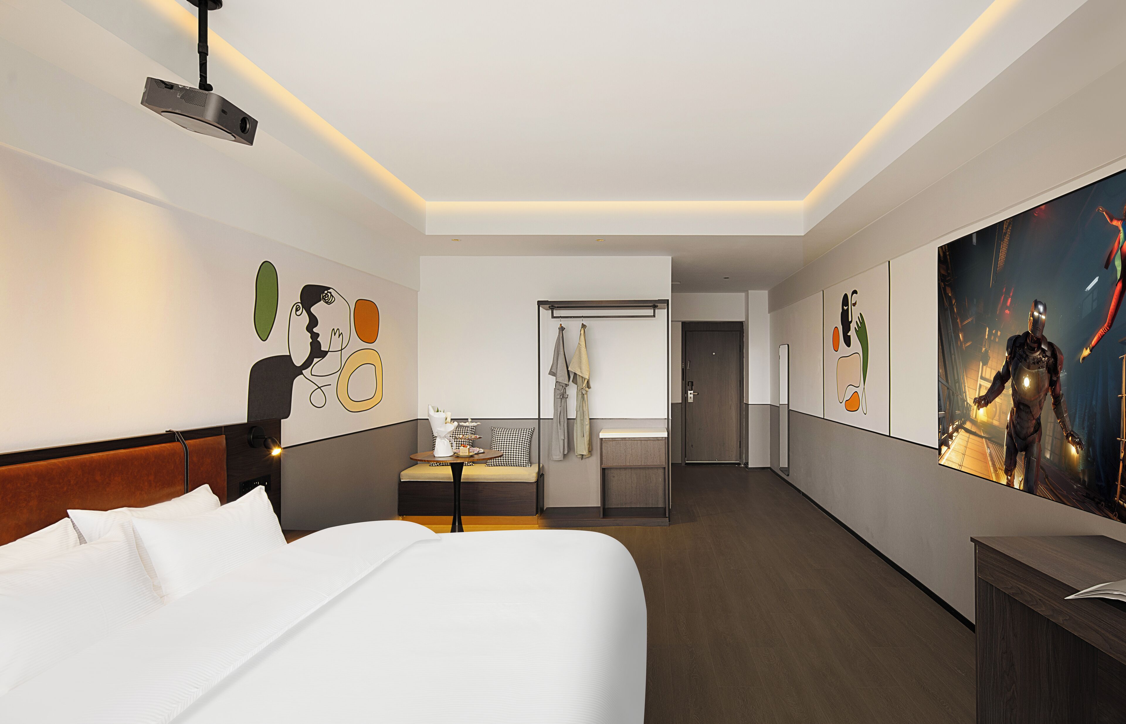 Una habitación de hotel moderna con una cama grande, un escritorio, un área de descanso y obras de arte en las paredes.