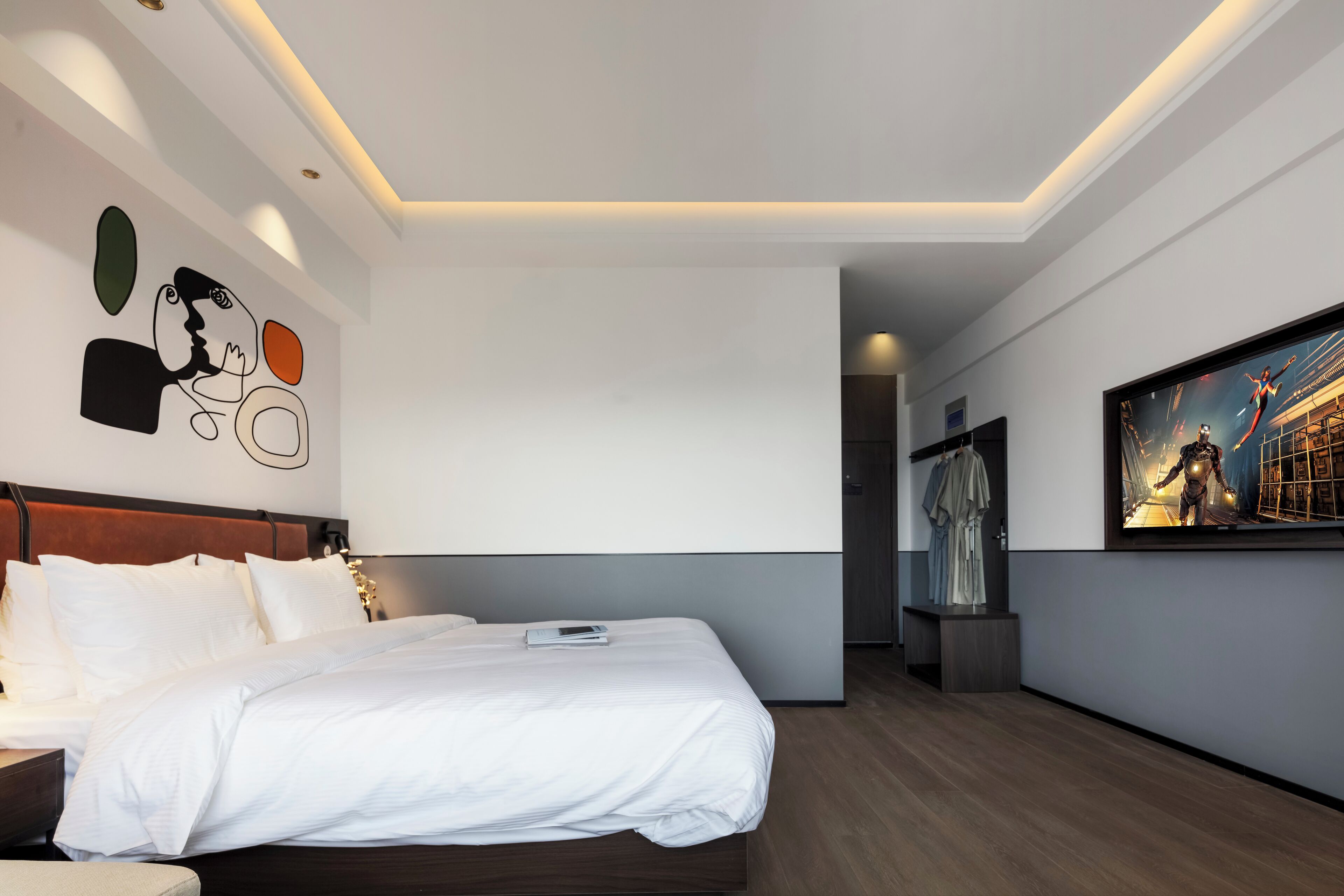 Ein modernes Hotelzimmer mit einem großen Bett, einem Nachttisch, einem Wandbild und einer Decke mit eingelassener Beleuchtung.