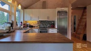 Eine moderne Küche mit Holzschränken, einem Edelstahlkühlschrank und einer großen Kochinsel mit Spüle.
