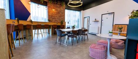 A modern office space with a brick wall, wooden bar area, and a meeting table with chairs.