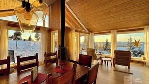 Un intérieur en bois comprenant un coin repas, de grandes fenêtres et une vue sur un paysage enneigé.