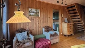 Interior acogedor de una cabaña con paredes de madera, una escalera y un comedor.