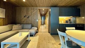 Un interno moderno con soffitto in legno, un divano, un tavolo da pranzo e un angolo cottura.