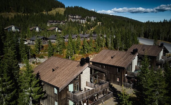 A resort with wooden cabins, a ski lift, and a mountain backdrop. - Modern ski-in/out apartment at Sjusjøen (Ringsaker)