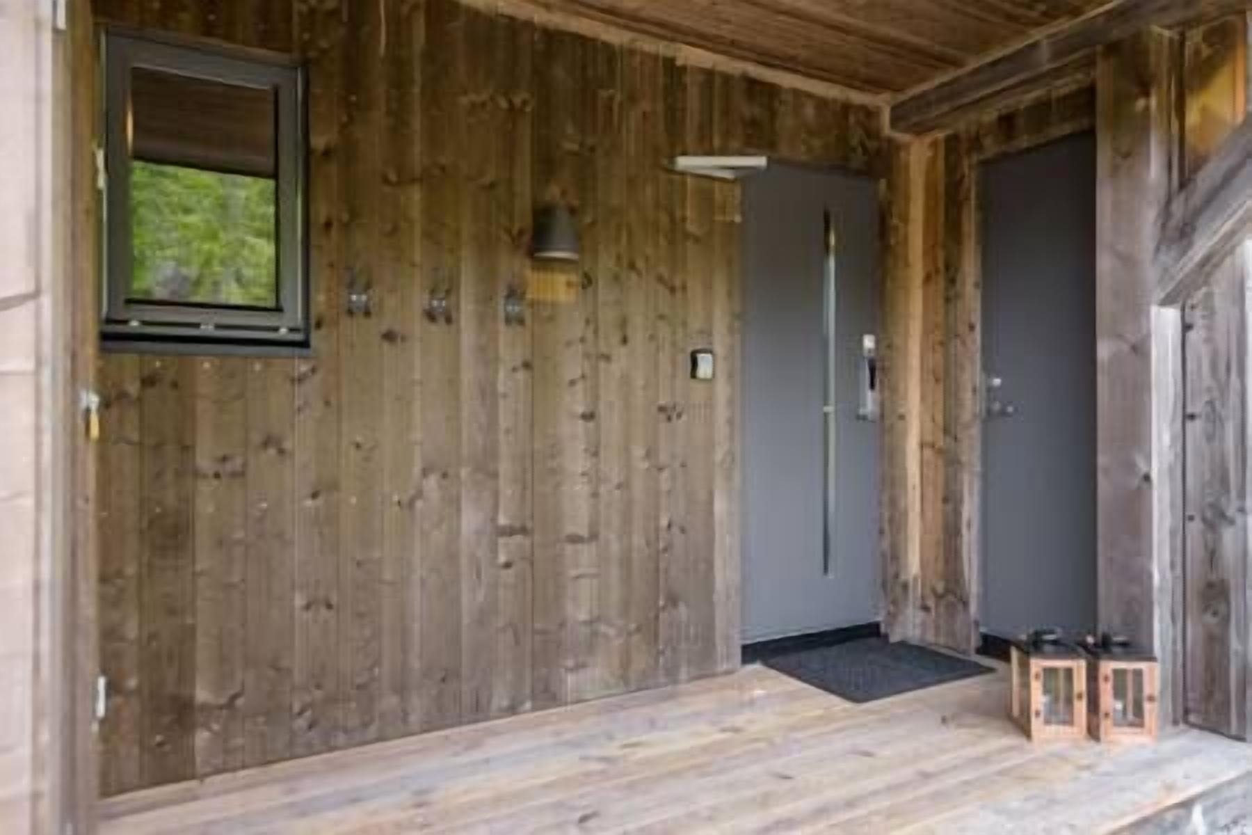 A wooden cabin with a large door, a small window, and a wooden bench outside.