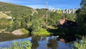 Eine friedliche Uferlandschaft mit einem kleinen Haus und einem Steg, der sich ins Wasser erstreckt.