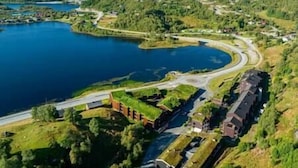 Ein Anwesen am Seeufer, mit einer sich um das Wasser schlängelnden Straße, umgeben von Grünflächen und einigen Gebäuden.