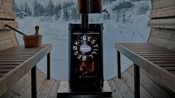 Ein Kaminofen in einer Hütte mit Blick auf eine verschneite Landschaft.