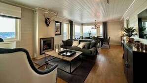 A spacious living room with a large window, a fireplace, a sofa, and a dining area. - Ski in/out, bbq, mountain view & fireplace - Hafjell (Øyer kommune)