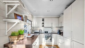 A modern kitchen with white cabinetry, a wooden countertop, and a built-in oven. - Ski in/out, bbq, mountain view & fireplace - Hafjell (Øyer kommune)