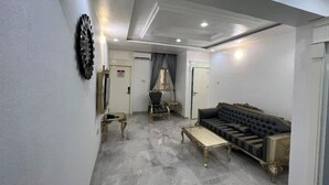 Un salon spacieux doté d’un sol en marbre, d’un canapé noir, d’une petite table et d’un miroir décoratif.