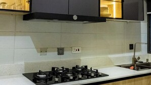 Une cuisine moderne dotée d’une cuisinière à gaz, de meubles noirs et d’une étagère intégrée pour ranger la vaisselle.