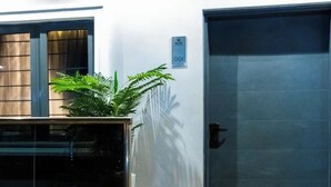 Une entrée moderne avec une porte en verre, un paillasson et une plante en pot.