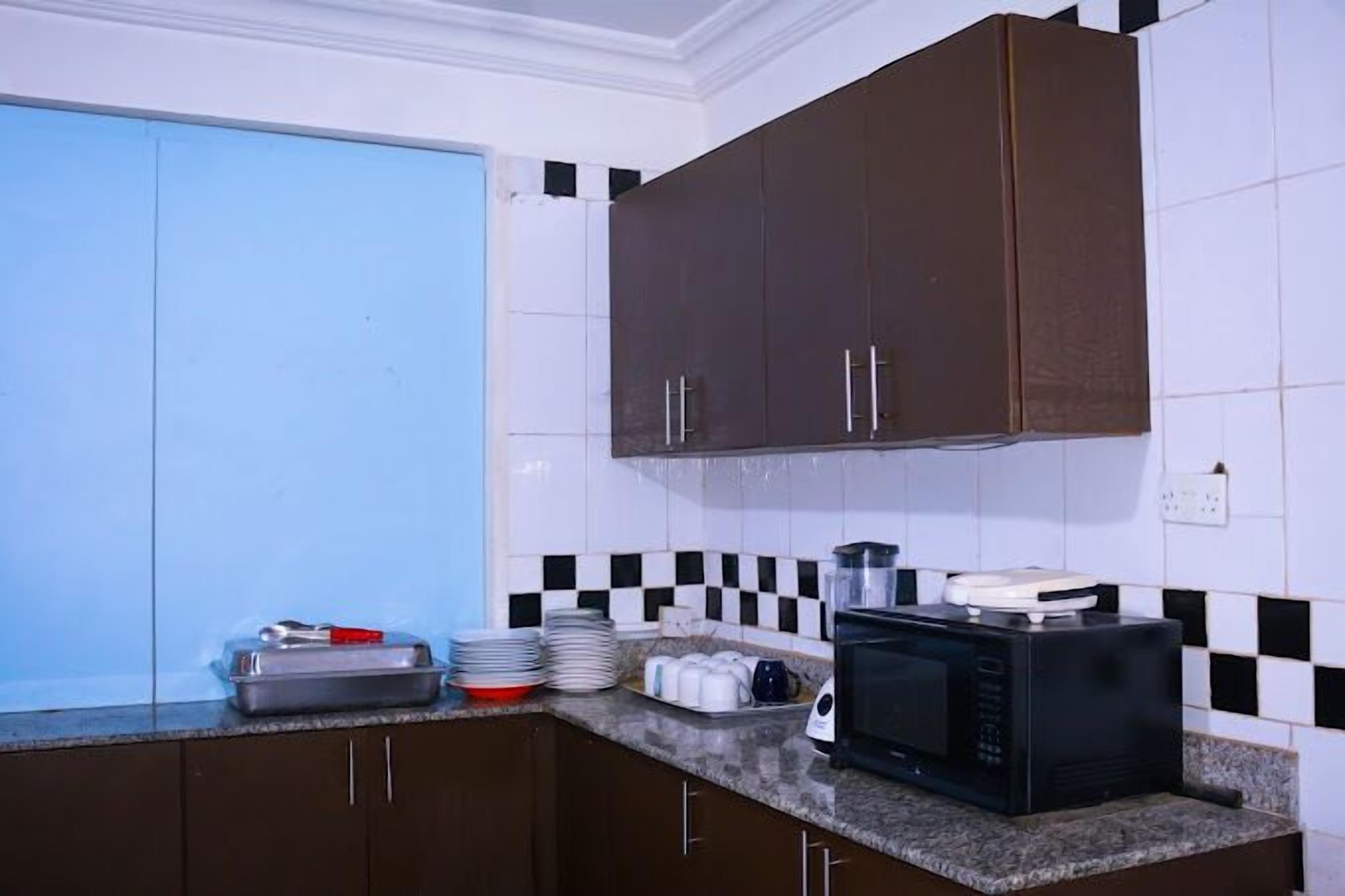 Una cucina con mobili marrone scuro, un forno a microonde e un lavandino.