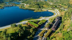 A lakeside property with a road curving around a central green area, surrounded by hills and a large body of water. - Cozy apartment in a central location in Sirdal (Sirdal kommune)