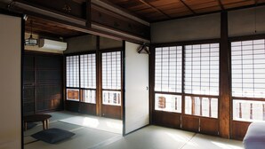 A traditional Japanese room with tatami flooring, sliding doors, and a view through large windows. - THE RITOMARU IKI KAZENO OYADO (Iki)