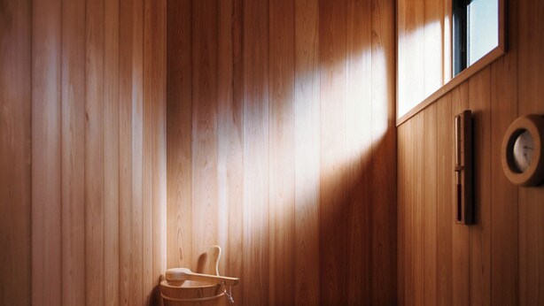 A wooden sauna with a bench, a wooden bucket, and a wall-mounted thermometer. - THE RITOMARU IKI KAZENO OYADO (Iki)