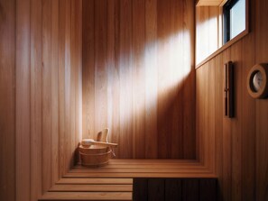A wooden sauna with a bench, a wooden bucket, and a wall-mounted thermometer. - THE RITOMARU IKI KAZENO OYADO (Iki)