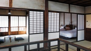 A traditional Japanese room with tatami flooring, a low wooden bed, and sliding shoji screens. - THE RITOMARU IKI KAZENO OYADO (Iki)