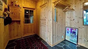 A wooden interior with a fireplace, a door with glass panels, a hanging coat rack, and a 'For Sale' sign. - Cozy spacious cabin with sauna at Natrudstilen (Ringsaker)