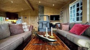 A cozy living room with two sofas, a wooden coffee table, and a fireplace. - Cozy spacious cabin with sauna at Natrudstilen (Ringsaker)