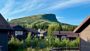 A residential area with houses, a prominent hill in the background, and a clear sky. - Cozy cottage in Skeikampen - close to Hafjell! (Gausdal)