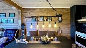 A modern dining area with a wooden ceiling, pendant lighting, and a central table with a floral centerpiece. - Cozy cottage in Skeikampen - close to Hafjell! (Gausdal)