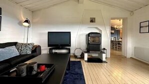 Een woonkamer met een bank, een flatscreen televisie, een open haard en een houten vloer.