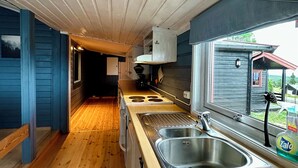 Een cabin interieur met een houten vloer, een keuken met een houten aanrecht, een raam en uitzicht op een cabin buiten.