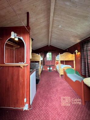 A cabin with wooden walls, a red carpet, bunk beds, a small table, and a window. - Large cabin Sjusjøen – XC ski in/out & lovely view (Ringsaker)