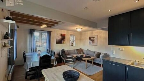 A modern living room with a dining area, a kitchen, and a large window.