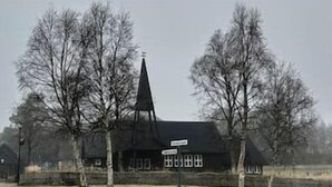 A rural church with a steeple, surrounded by leafless trees and a fence.