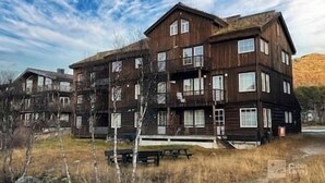 A multi-story wooden building with balconies, a picnic table, and a clear sky.