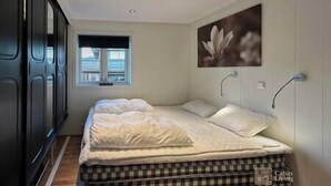 A bedroom with a bed, a window, and a painting on the wall.
