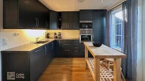 A modern kitchen with dark cabinets, a wooden countertop, and a built-in oven.