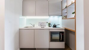 A compact kitchen with a built-in oven, a sink, and a microwave. - Student Only Stoneworks (Brighton)