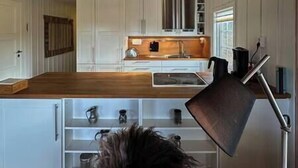 Una cocina moderna con armarios blancos, encimera de madera y estufa integrada.