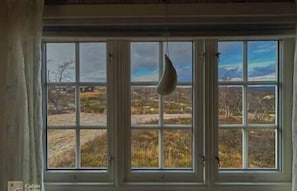Enjoy a serene view of the surrounding landscape from the large window with multiple panes.