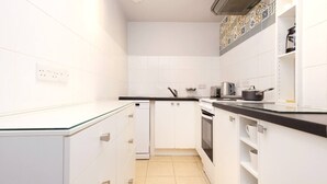 Eine moderne Küche mit weißen Schränken, einer schwarzen Arbeitsplatte und einer gefliesten Spritzschutzwand.