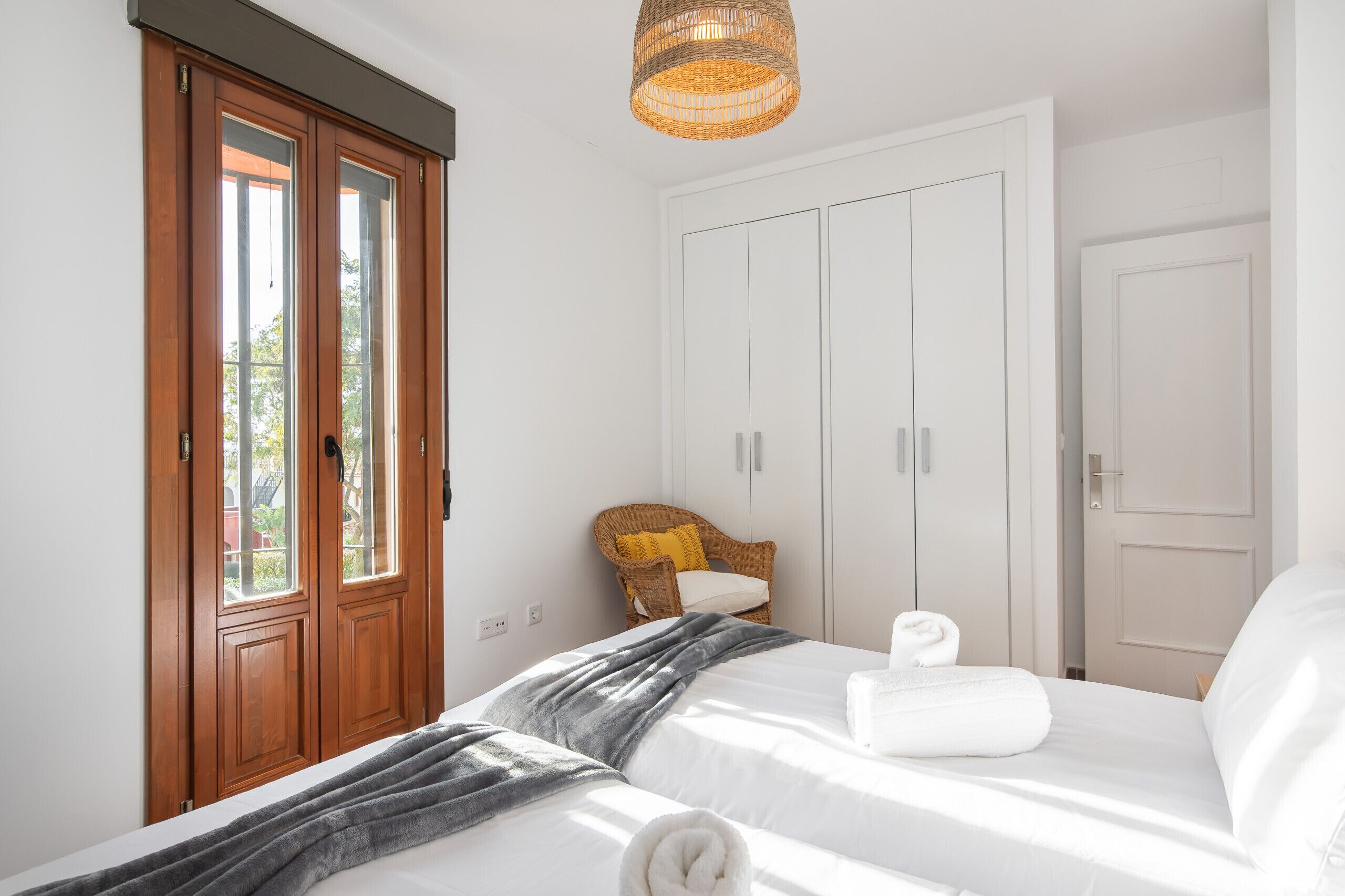 A bedroom with a bed, a chair, a wardrobe, and a window.