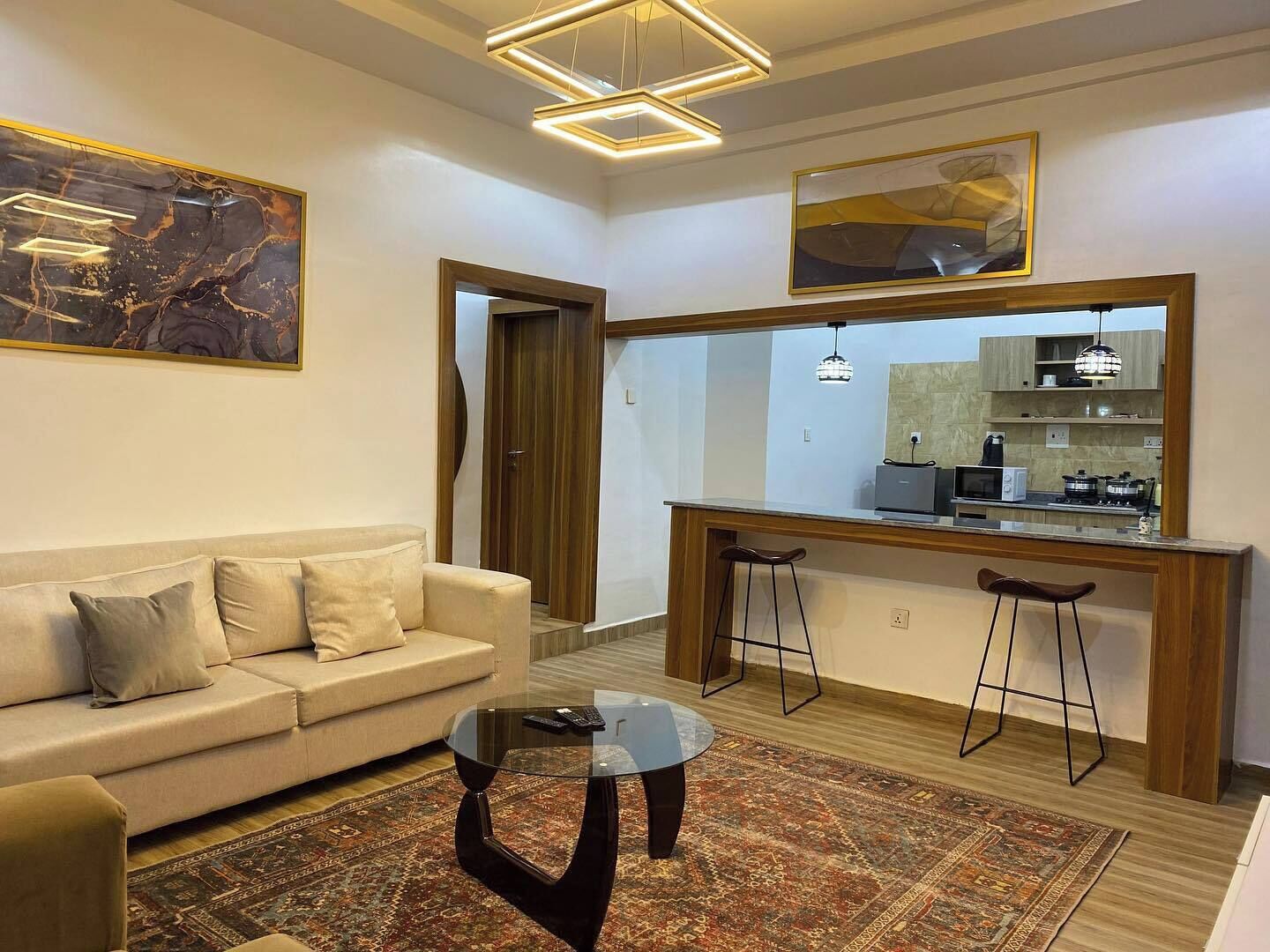 Uma sala de estar moderna com sofá, mesa de centro e área de cozinha com banquetas.