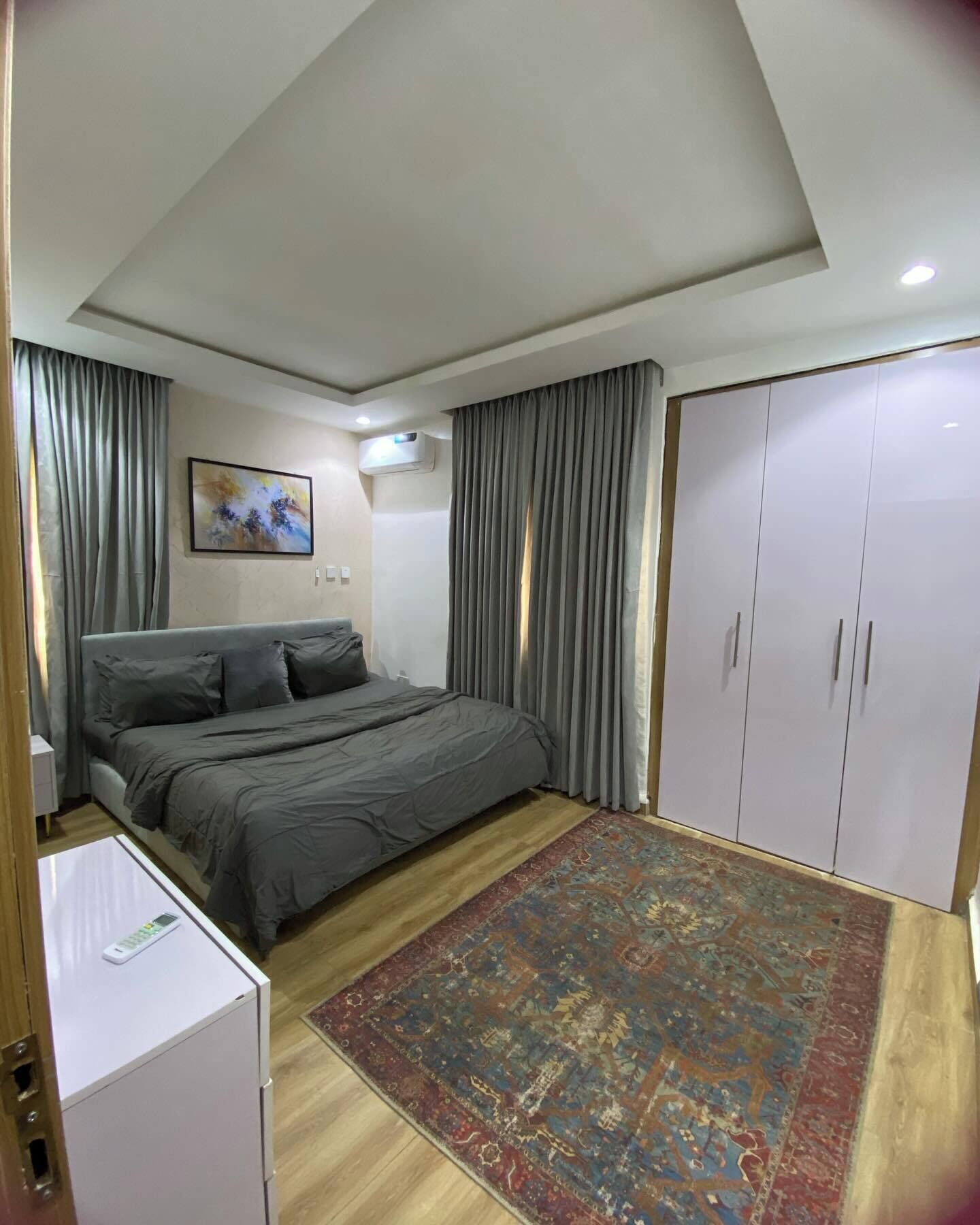 Ein Schlafzimmer mit Bett, Kleiderschrank, kleinem Tisch und Teppich.